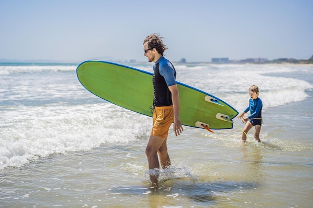 Padre o instructor enseñando a su hijo a surfear en el mar en vacaciones o viajes de vacaciones y