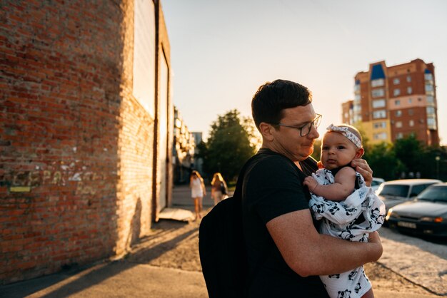 Padre padre sosteniendo a un bebé recién nacido niña en las manos al aire libre verano atardecer noche