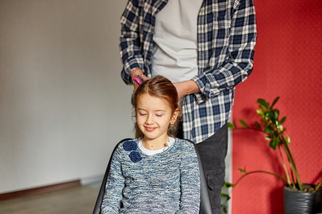 Padre peinando, cepillando el cabello de su hija en casa, padre e hija sonriendo, momentos familiares, pasando tiempo juntos.