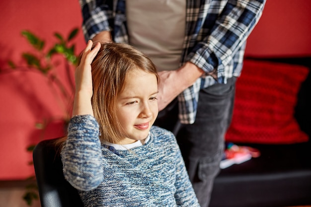 Padre peinando, cepillando el cabello de su hija en casa