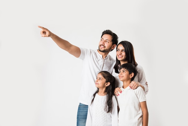 Padre señalando con el dedo mientras está de pie con su esposa e hijos sobre fondo blanco. enfoque selectivo