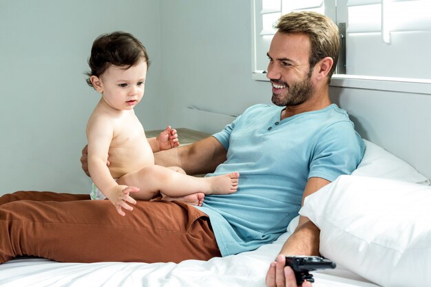 Padre sentado con bebé en la cama