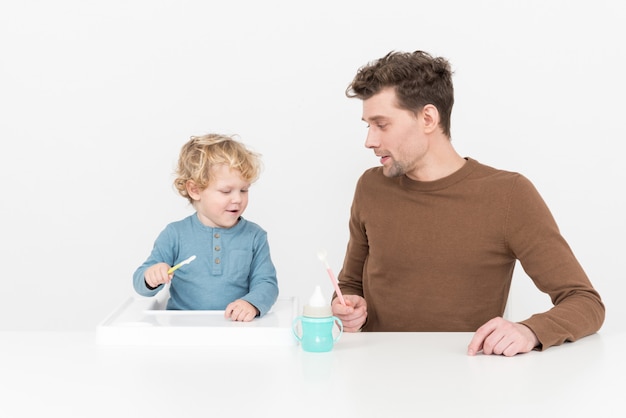 Padre sentado a la mesa y alimentando a su hijo bebé