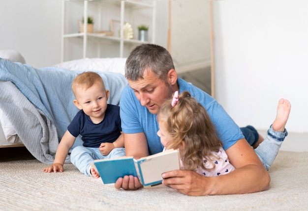 Padre sentado en el piso y leyendo para niños