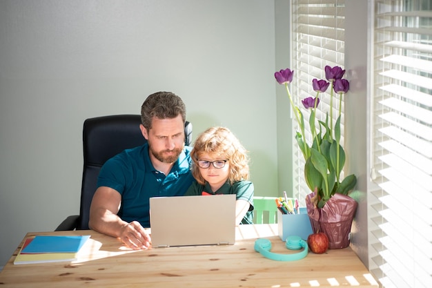 Padre serio ayudando a su hijo de la escuela a estudiar con una laptop en casa nerd