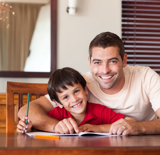 Padre sonriente ayudando a su hijo para la tarea