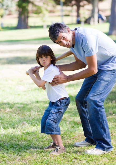 Padre sonriente enseñando béisbol a su hijo