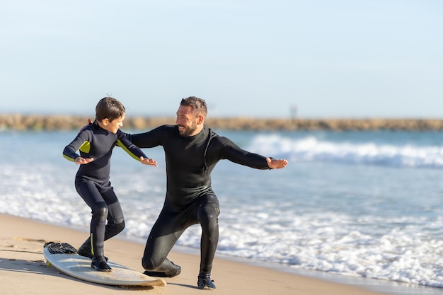 Padre sonriente enseñando a su hijo a surfear