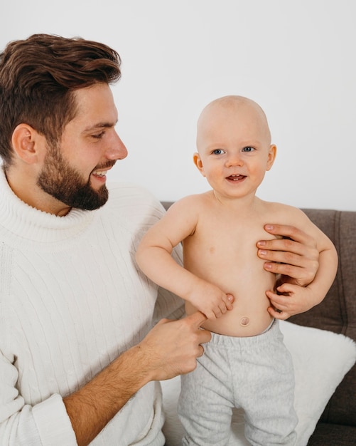 Padre sonriente pasar tiempo con su bebé en casa