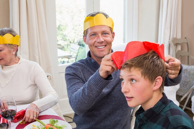 Padre sonriente poniendo sombrero de fiesta en la cabeza de los hijos