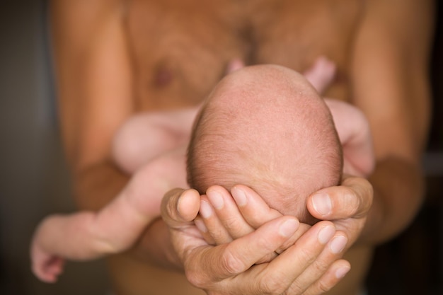 Padre sosteniendo la cabeza de su hijo recién nacido en las manos