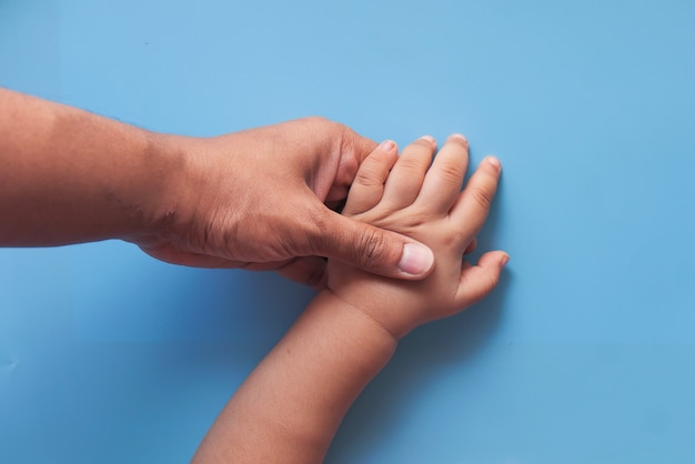 Padre sosteniendo la mano del bebé, de cerca.