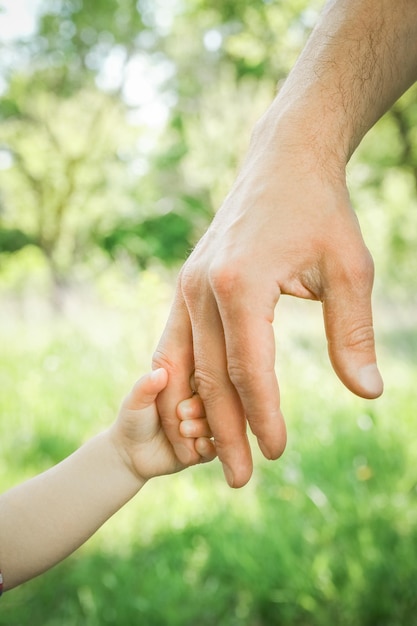 El padre sosteniendo la mano del niño con un fondo feliz