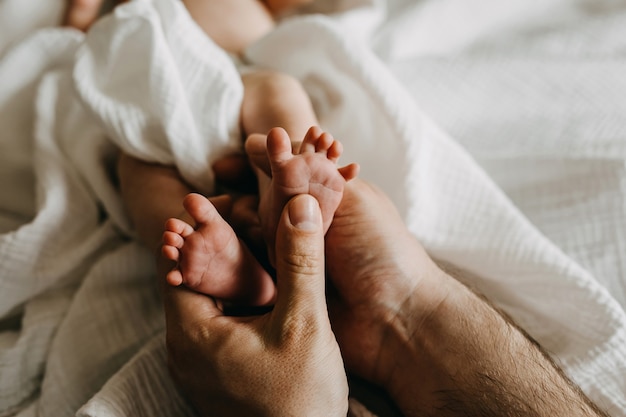 Padre sosteniendo pequeños pies de bebé recién nacido
