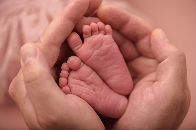 Padre sosteniendo las piernas de un bebé recién nacido en sus manos