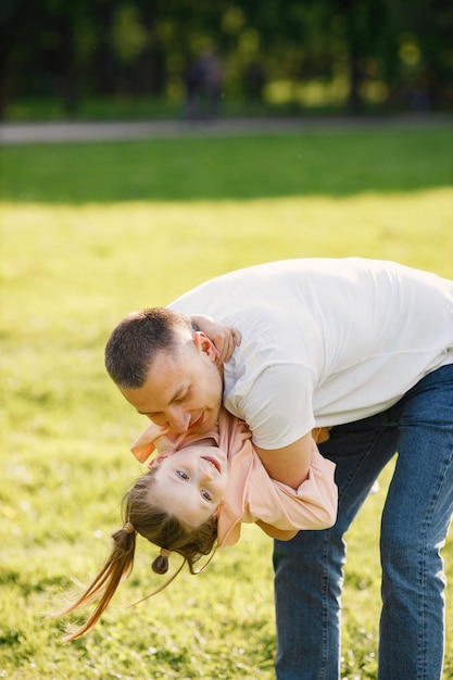 Padre sosteniendo a su hija en sus manos y abrazándose en un parque de primavera