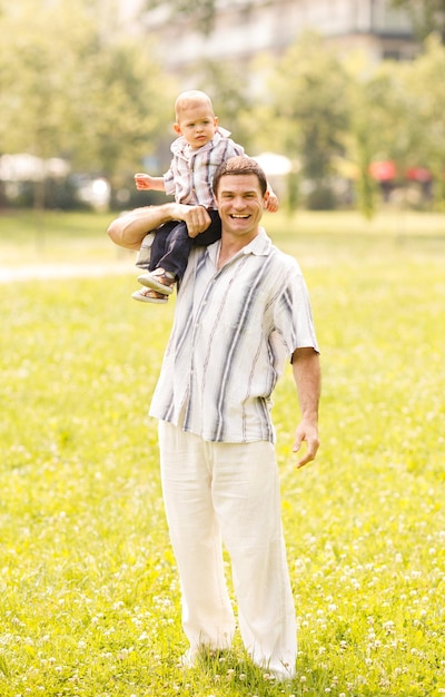 Padre sosteniendo a su hijo en el hombro y caminando por el parque