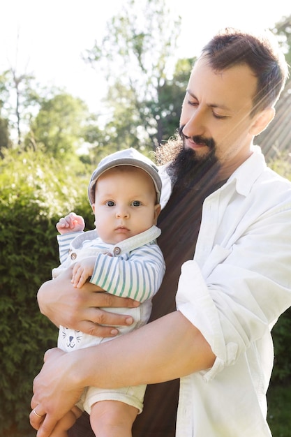 padre sosteniendo a su hijo en sus brazos sobre un fondo de vegetación