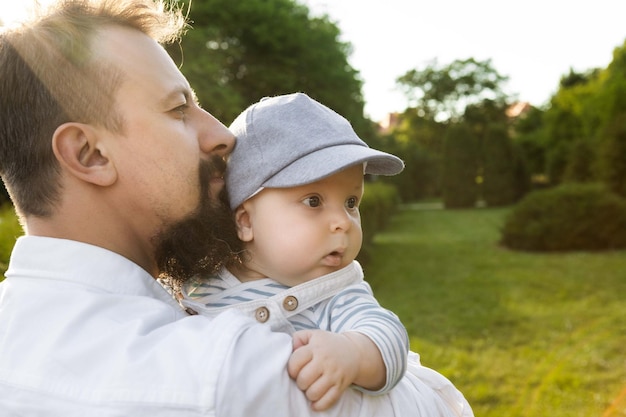 padre sosteniendo a su hijo en sus brazos sobre un fondo de vegetación