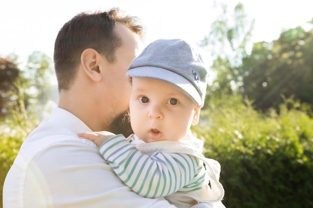 padre sosteniendo a su hijo en sus brazos sobre un fondo de vegetación