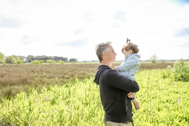 Padre sosteniendo a su pequeña hija en sus brazos en el campo