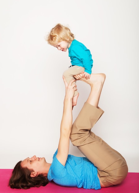 Padre sosteniendo a su pequeño hijo en sus pies yoga familia feliz