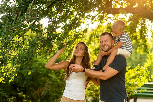 El padre sostiene al niño en su brazo y los padres juegan con el niño al aire libre.