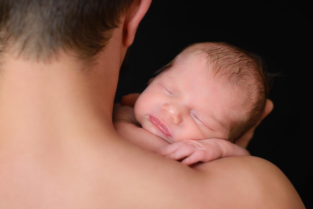 Un padre sostiene a un bebé recién nacido en su hombro.