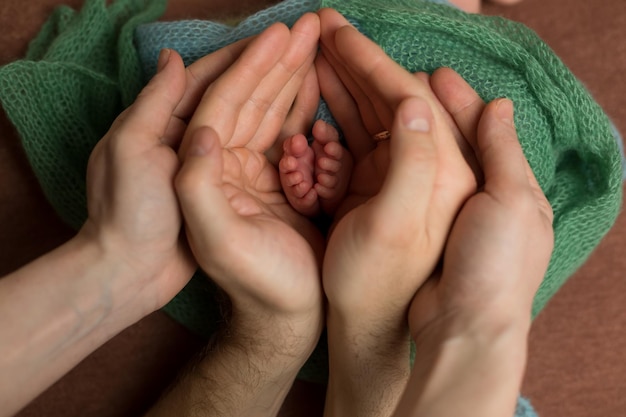 Foto un padre sostiene las manos de un bebé y las manos de un bebé sostienen los pies del bebé.