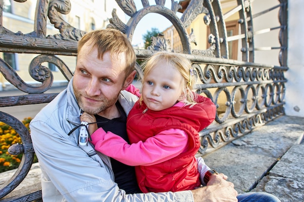 El padre sostiene a la niña de años durante la caminata en el centro de la ciudad