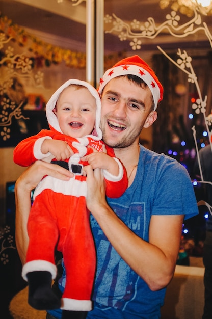 El padre sostiene en sus manos a un niño vestido como Santa Claus