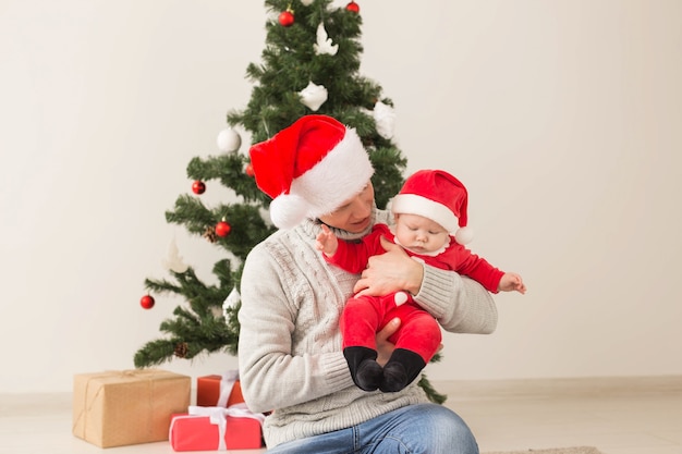 Padre con su bebé con gorro de Papá Noel celebrando la Navidad.