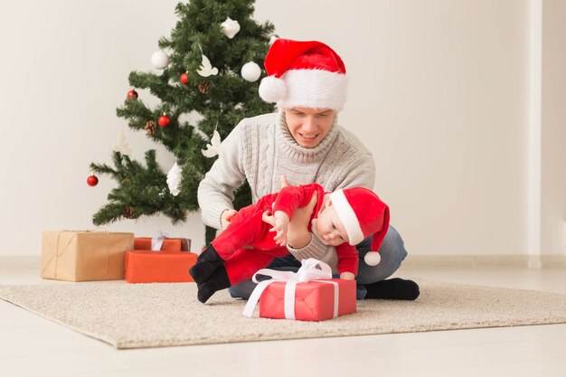 Padre con su bebé con gorro de Papá Noel celebrando la Navidad.