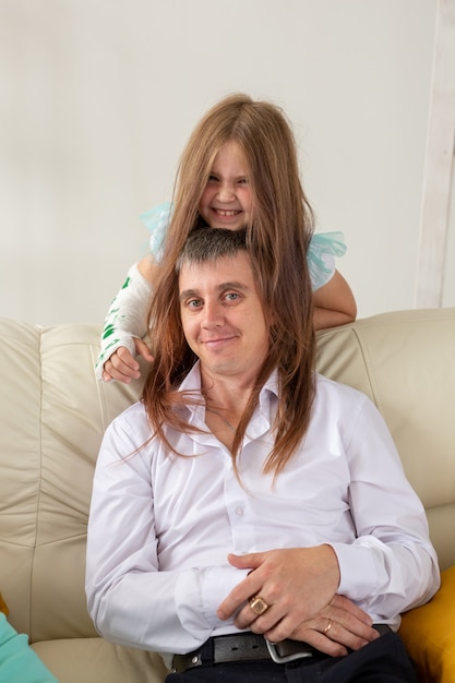 El padre y su hija se divierten en su sala de estar, la niña tiene una lesión en la mano, pero ella es