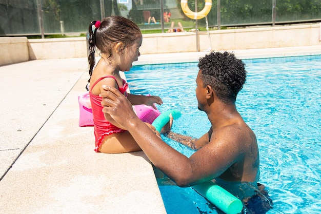 Padre con su hija triste en la piscina