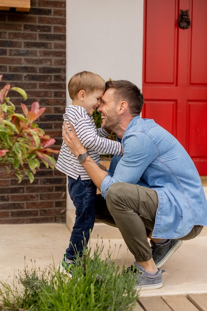 El padre y su hijo se divierten frente a la puerta de la casa.