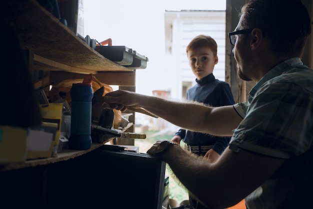 El padre y su hijo pequeño trabajan juntos en el garaje el concepto de aprendizaje en familia