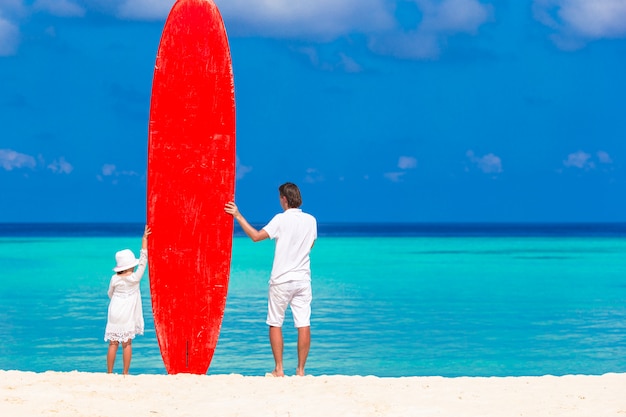 Padre y su hijo con tabla de surf durante las vacaciones de verano