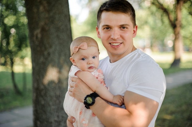 Padre con su pequeña hija en las manos en el parque