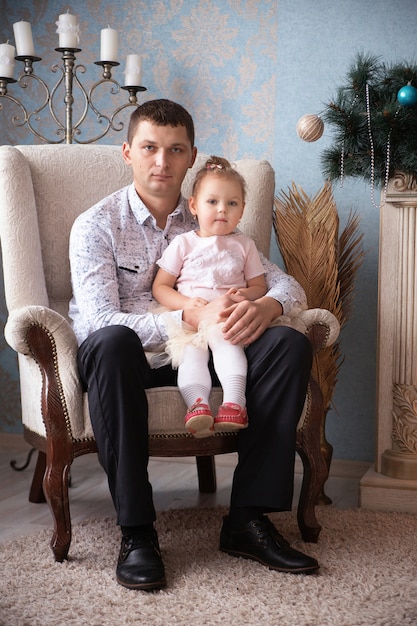 Padre con su pequeña hija sentada en el sillón