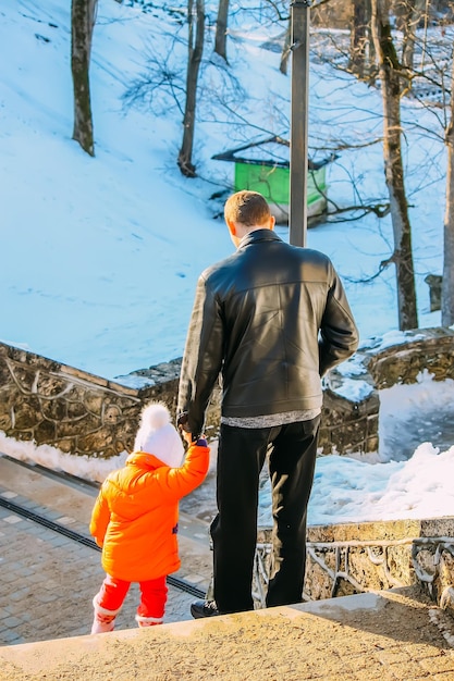 El padre y su pequeña y linda hija se divierten al aire libre en el día de invierno