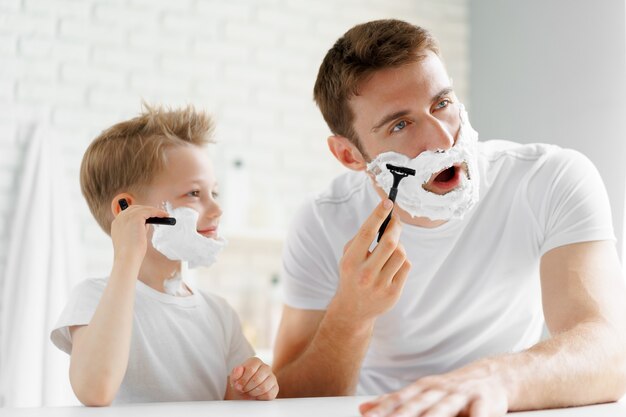 Padre y su pequeño hijo afeitándose juntos en el baño.