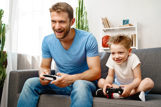 Padre y su pequeño hijo jugando videojuegos juntos en casa