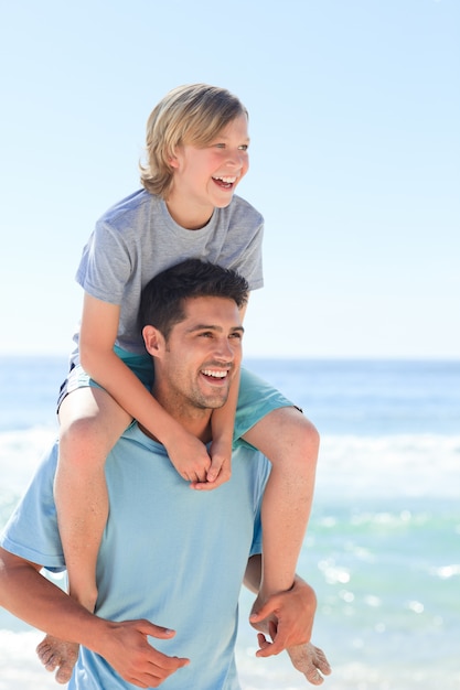 Padre teniendo hijo a cuestas en la playa