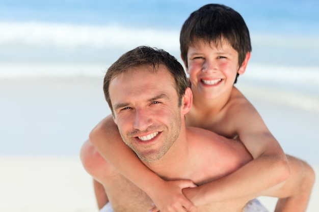 Padre teniendo hijo a cuestas en la playa