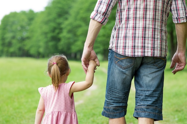 El padre tiene la mano de un niño pequeño y camina