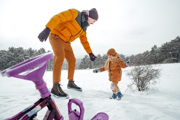 Padre tirando de un hijo pequeño en trineo en invierno