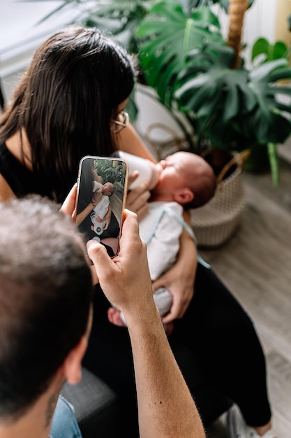 Foto padre tomando una foto del bebé con el celular mientras el bebé come