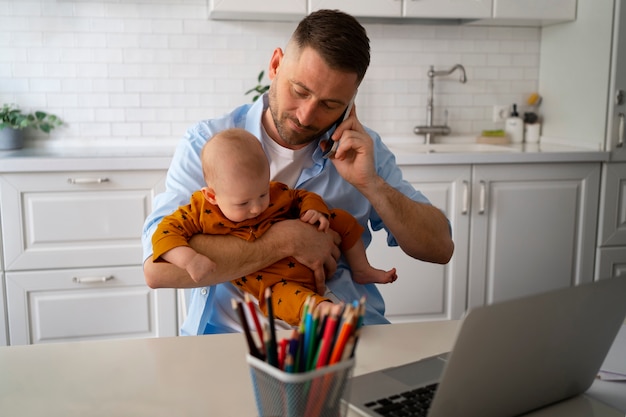 Padre trabajando desde casa tratando de equilibrar la vida familiar con el niño y el trabajo