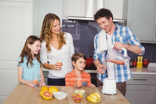 Padre vertiendo jugo de fruta en vaso con familia